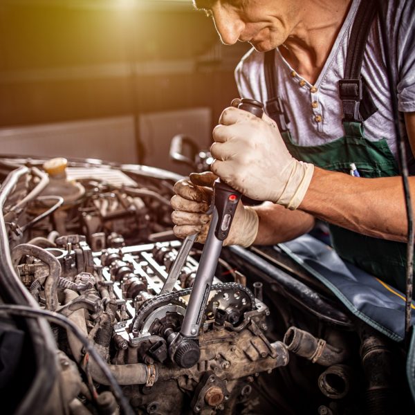 Mechanic with wrench working and repair car engine in car service centre